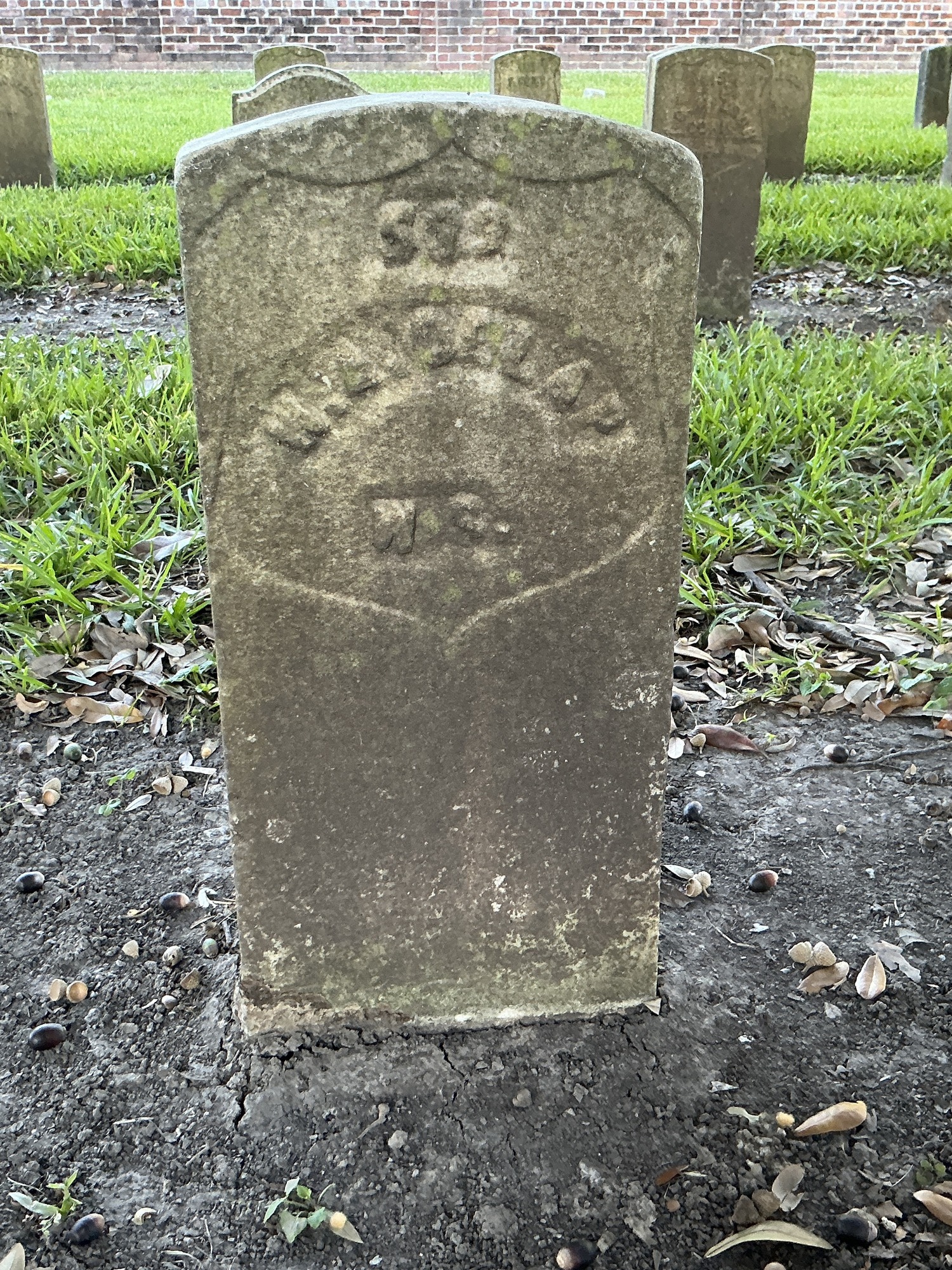 Front of historic upright marble headstone with recessed shield with recessed lettering face.