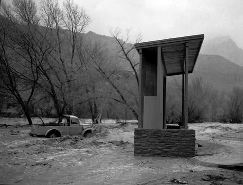 The December 6, 1966 flood damage - in Watchman campground near amphitheater. Image shows truck caught in water current.