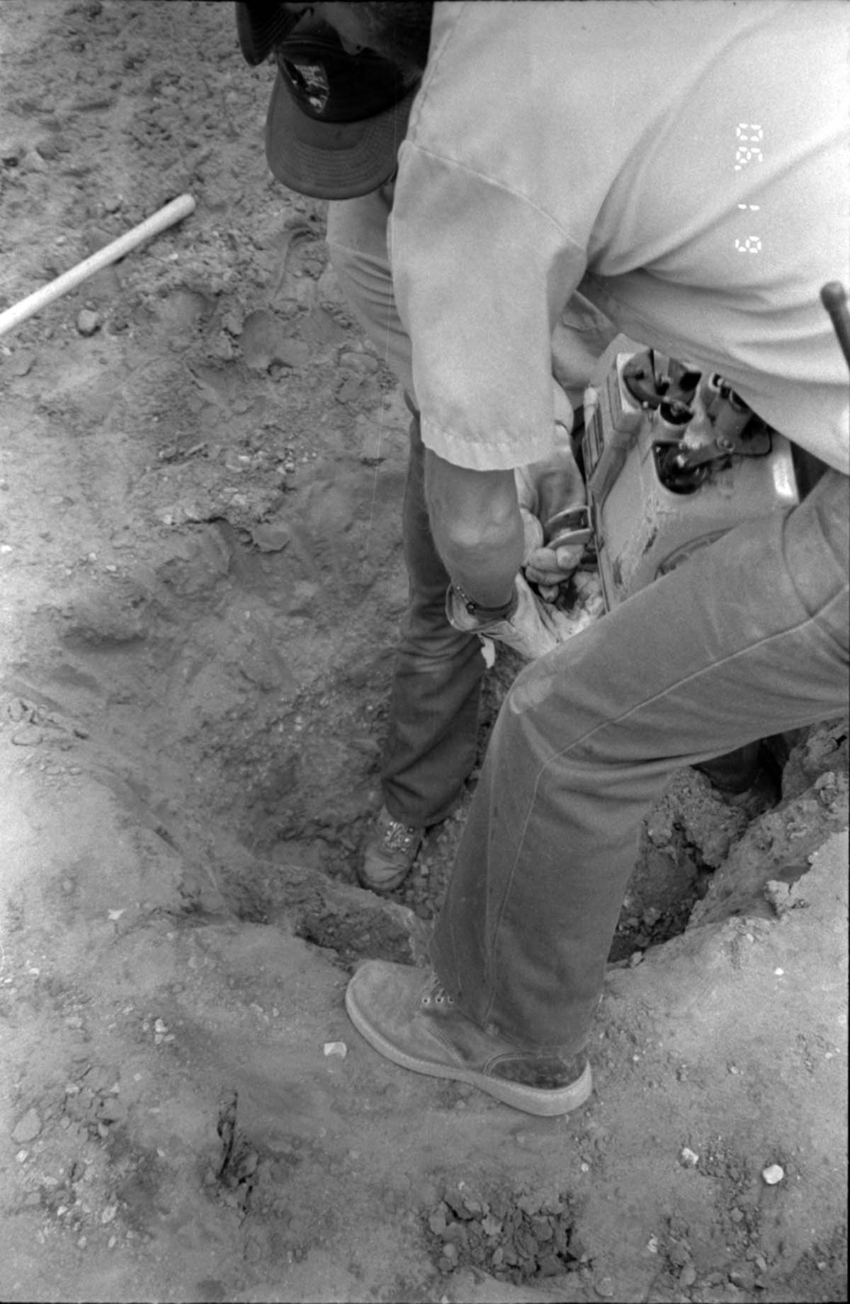Men operating construction machinery while digging a hole during the construction of headquarters addition.