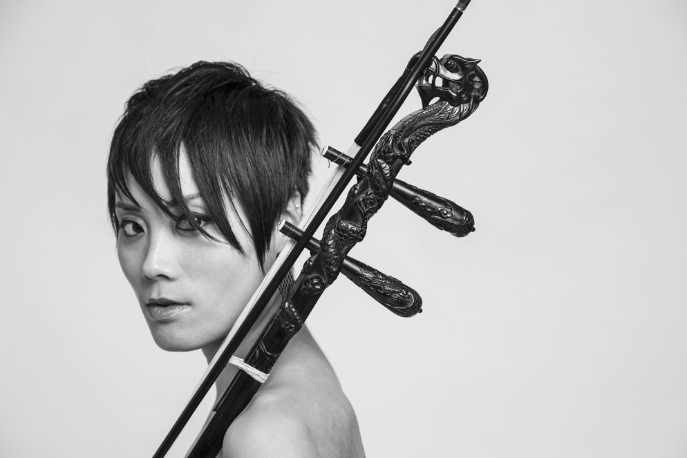 Portrait photo of a musician holding an Asian stringed instrument called an erhu