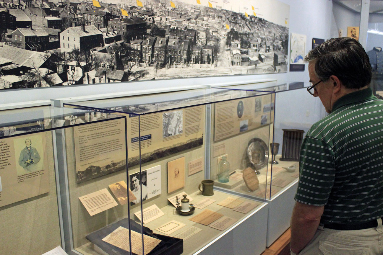 A man viewing objects in a museum display case.