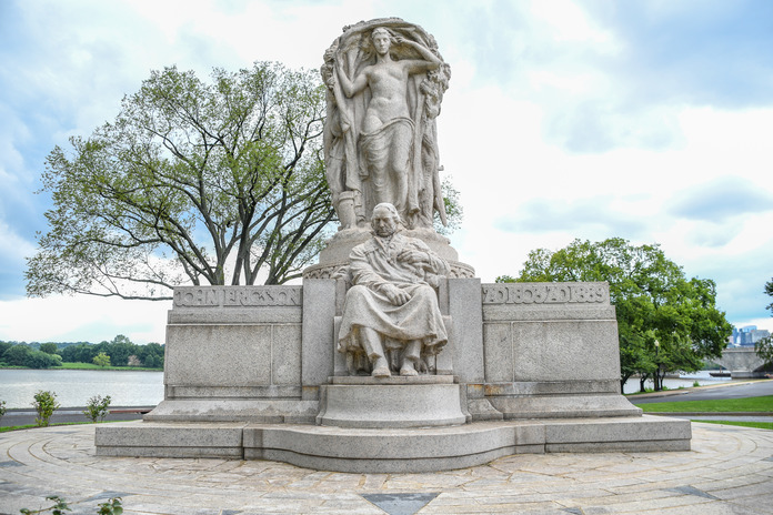 A granite statue of John Ericsson seated is at the center with the allegorical statue of "labor" standing behind him, on the left side of Ericsson it reads "John Ericsson" and on the right side it reads "AD 1803 AD 1889".