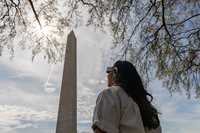 A visitor watch the partial eclipse over the Washington Monument