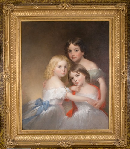 Portrait of three girls in white off-shoulder dresses and colored sashes embracing each other