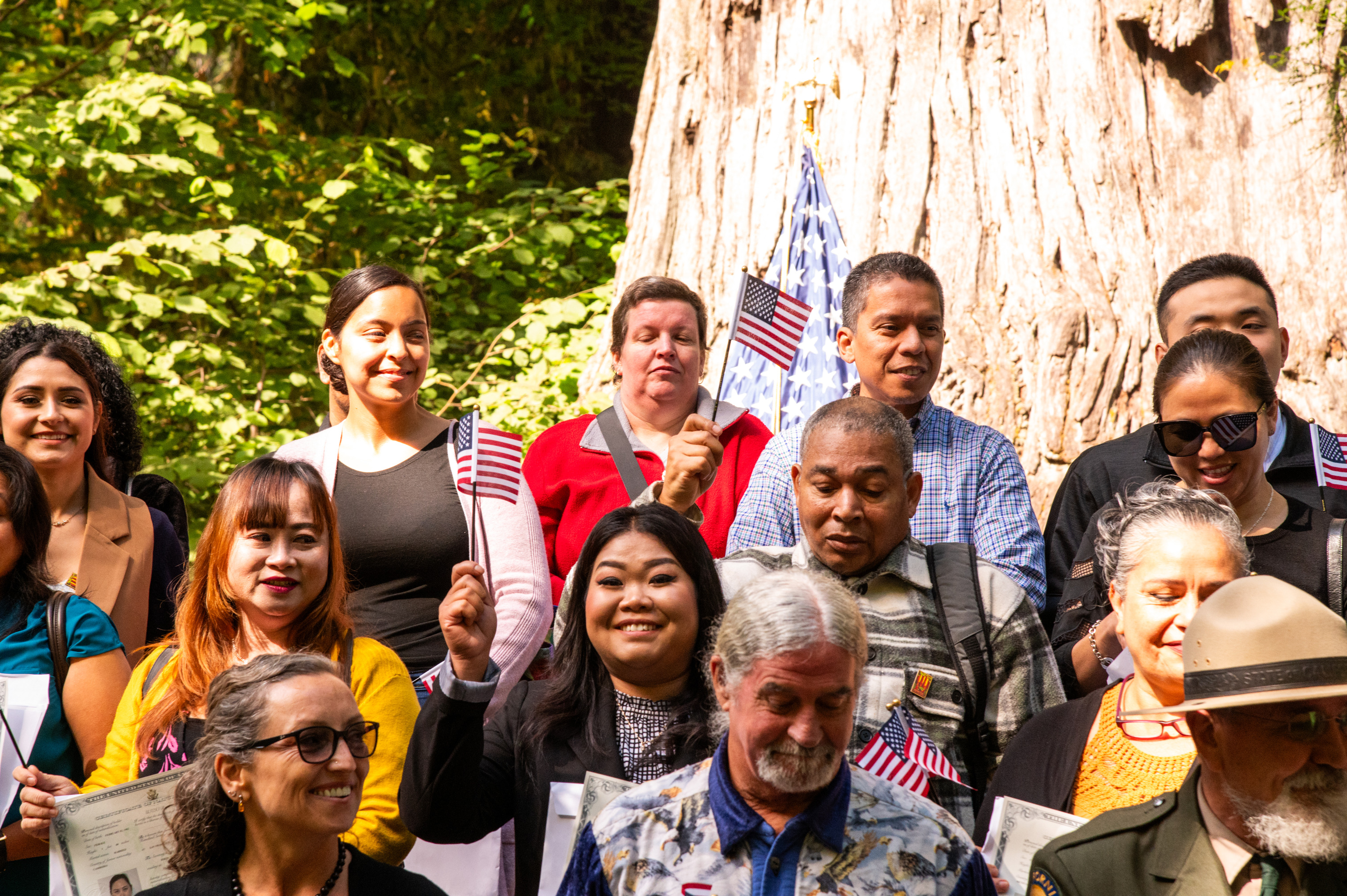 Three rows of people pose with small USA flags