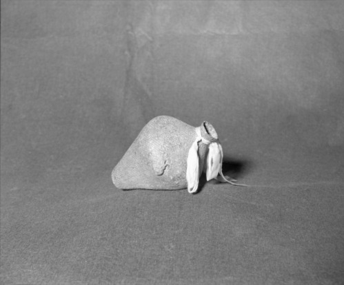 Mrs. Donald Segerstrom Collection. Object: Paiute water jug. Dimensions: 7 1/2" height. Materials: Willow, pine pitch, red clay, cordage handle, ribbon. Technology: Three strand start, diagonally twined body of basket, one row three-strand twining and one row plain twining at neck finish, rods trimmed off flush. Photographed by Michael Dixon. Catalogued by Craig Bates and Barbara Beroza. Yosemite Collections, National Park Service. 1/83.