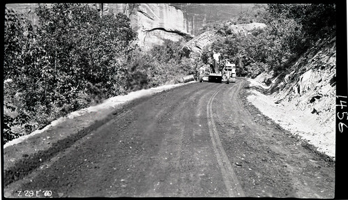 Workers engaged in experimental road paving of the floor of the valley road, smoothing the processed material to ready it for compaction.