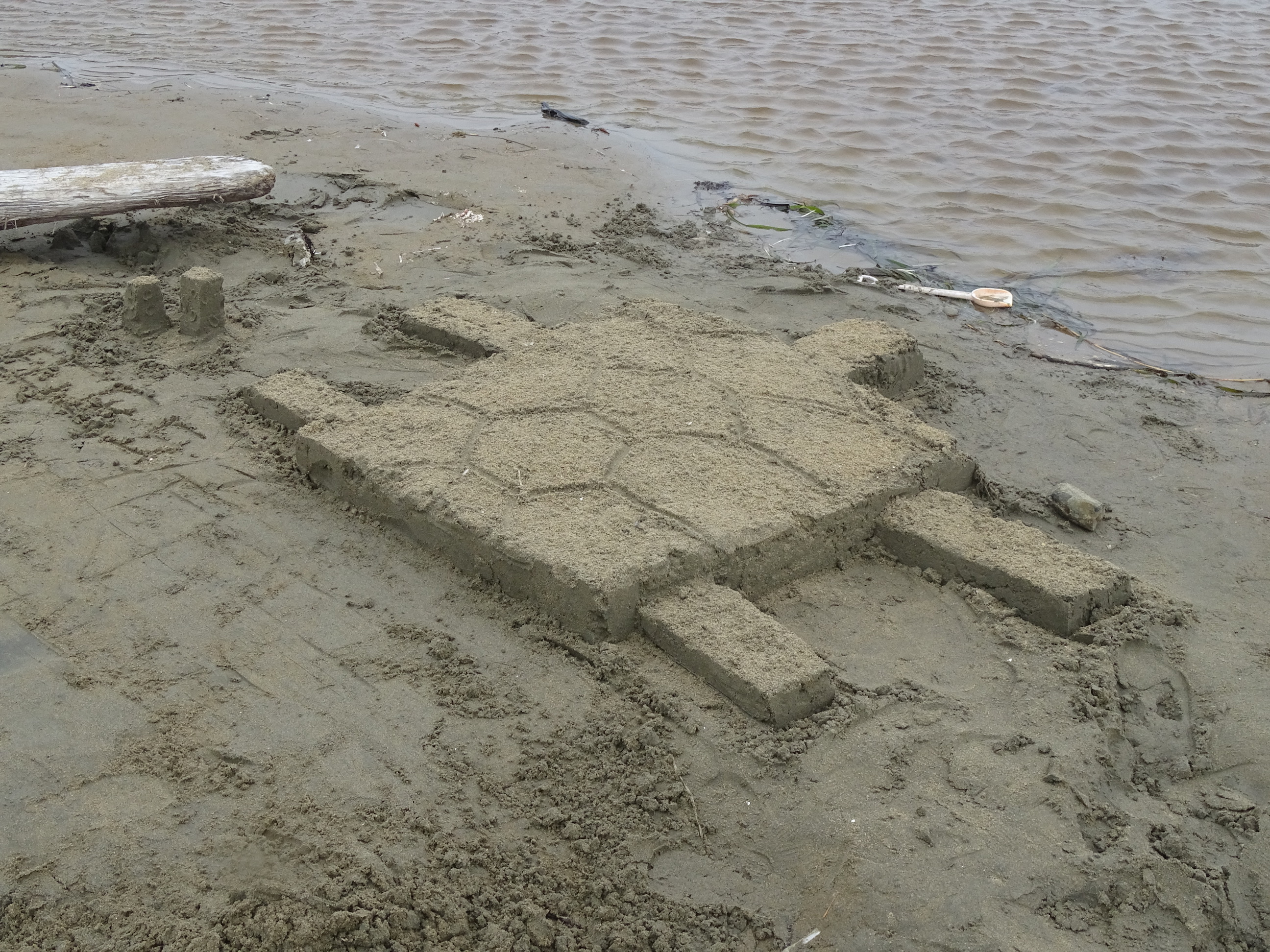 A sand sculpture of a sea turtle with a Minecraft theme, e.g., a turtle with blocky square and rectangular body, head, and flippers.