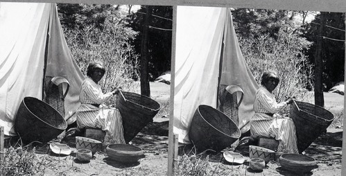 Copy Neg: 11/85 by M. Dixon; Stereo from L. Smaus collection; silver print on grey card. Native American Mary repairing a Western Mono Burden basket. The other baskets set about are from Boysen's collection. Same image (YM-8409)