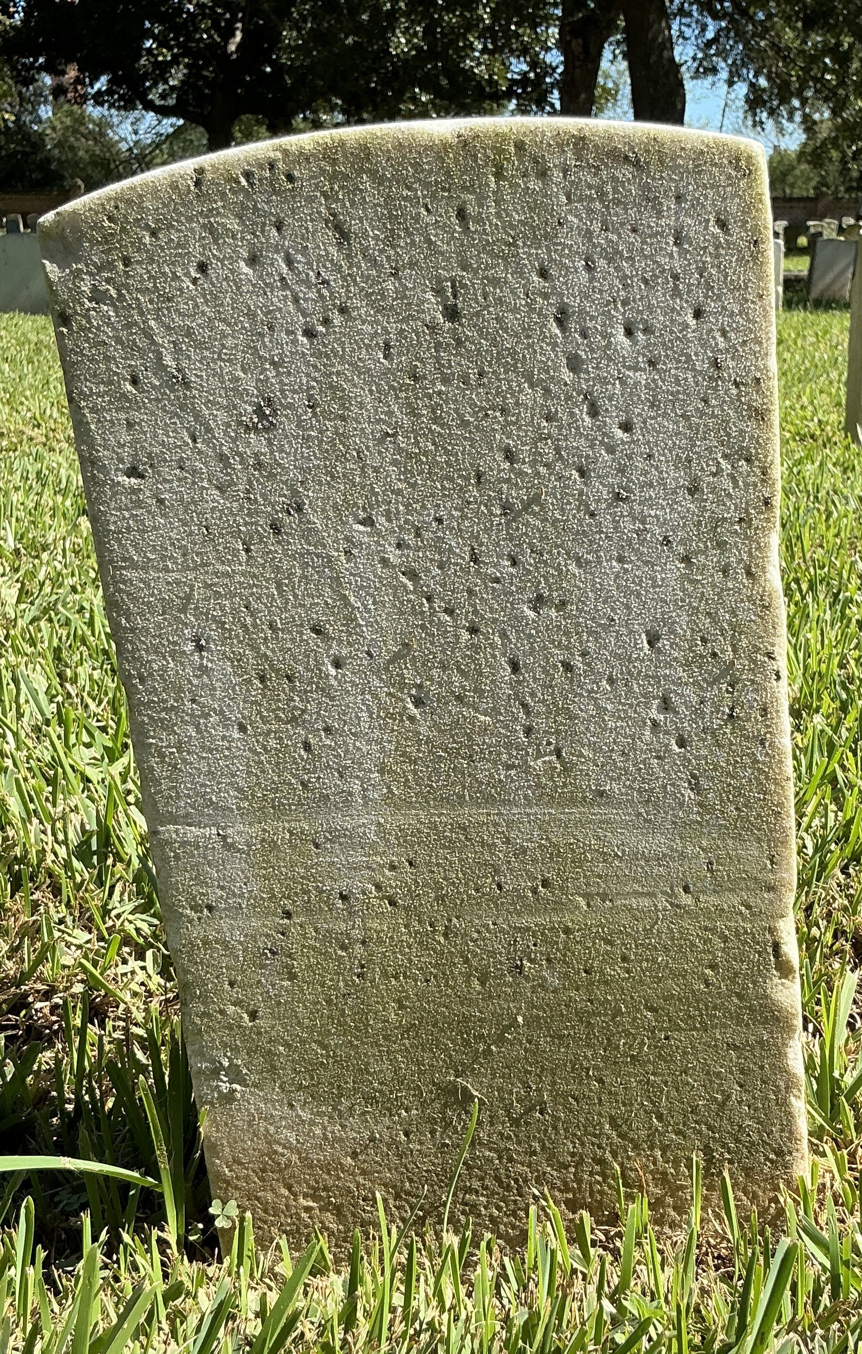 Back of historic upright marble headstone with recessed shield face.