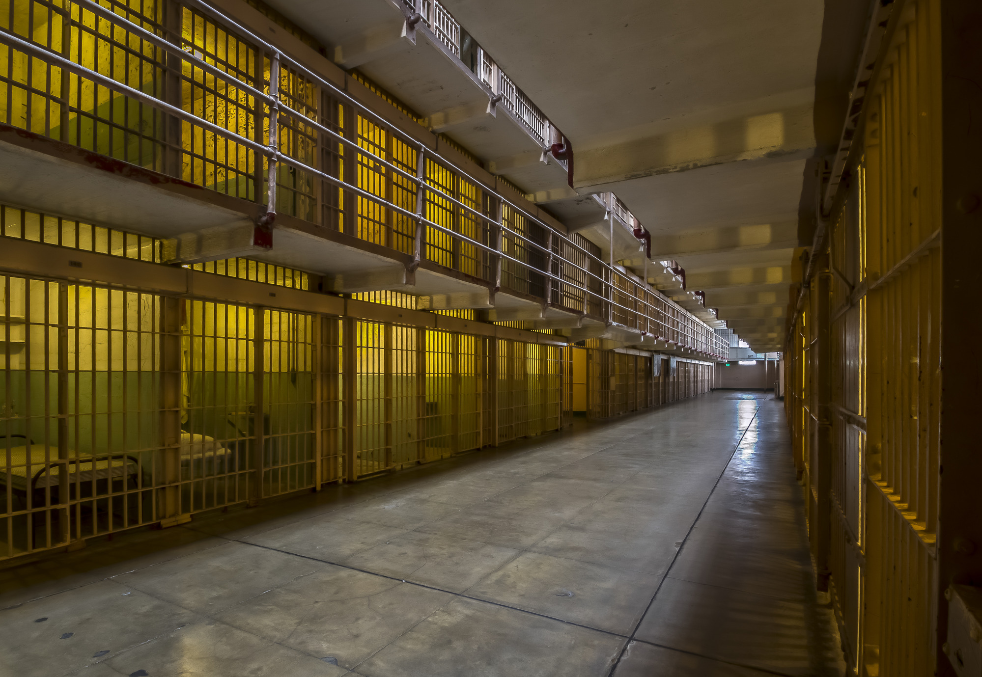 Evening light in the  main cell block, shown from the doorway of a cell looking at the other wall of cells.
