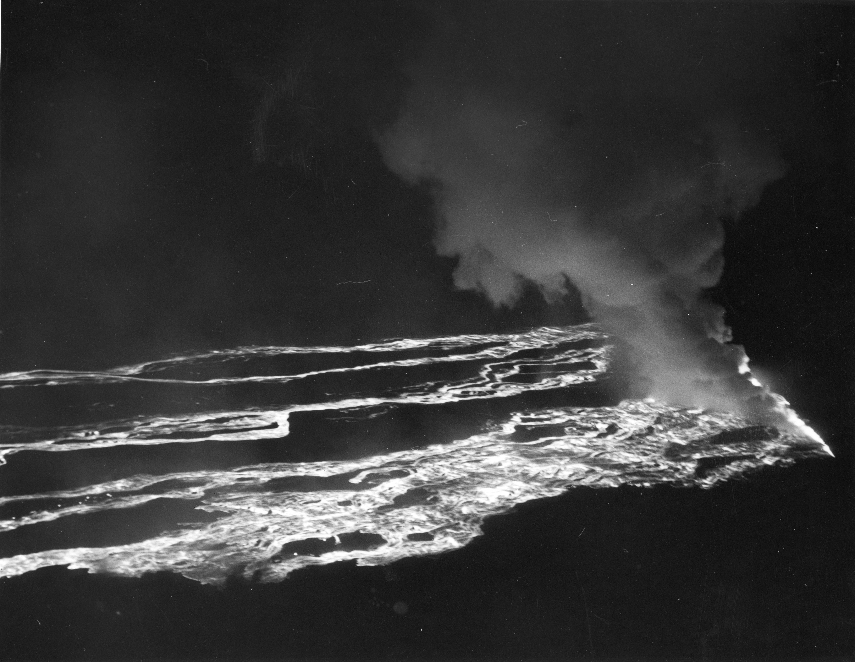 Black and white aerial photo of lava flows at night