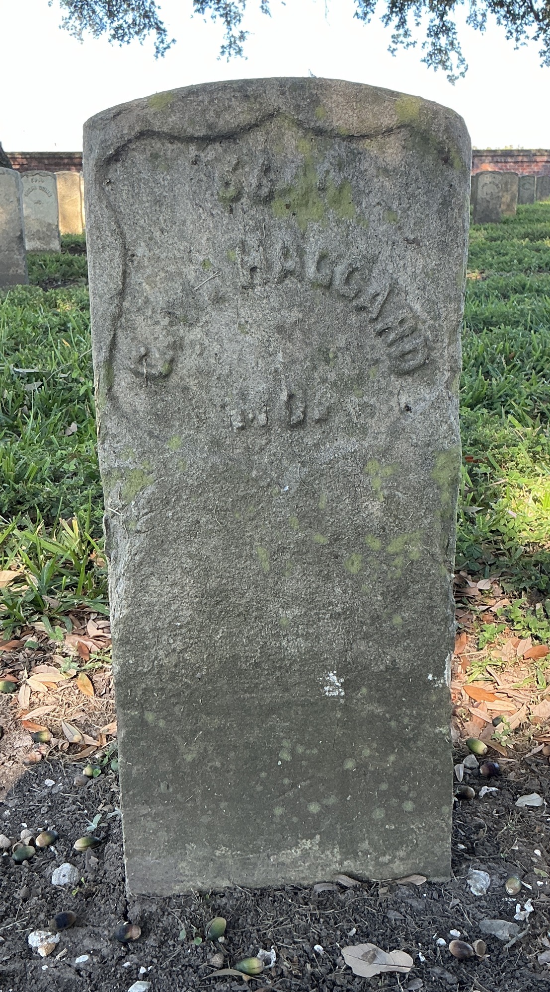 Front of historic upright marble headstone with recessed shield face.