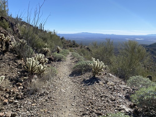 narrow trail on the edge of the ridge with mountains in the distance