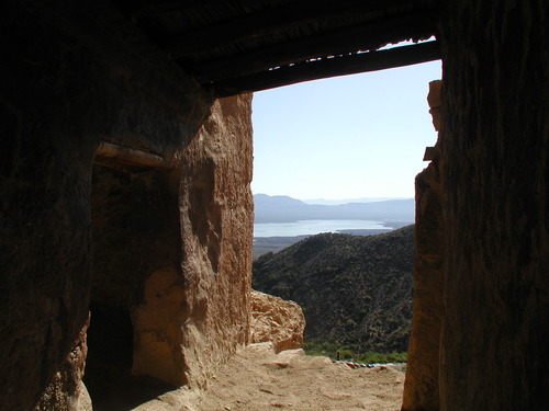 View looking out of a cliff dwelling doorway toward a valley and lake.