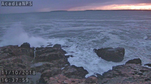 Big wave against rocks near sunset