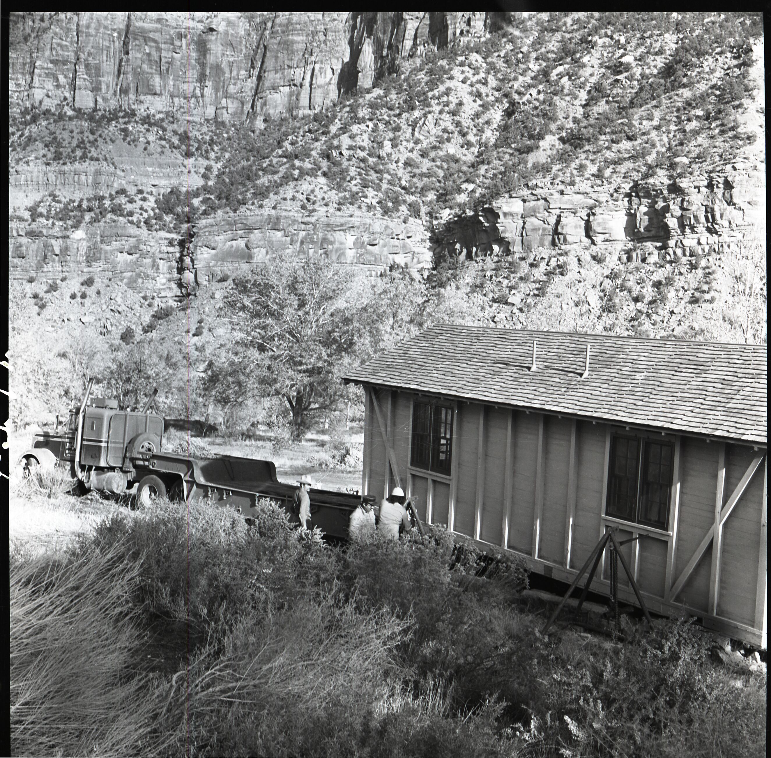 Kaibab-Paiute Tribe members working to jack up one of the Zion Inn cabins to load on trailer prior to removal. Cabins were located near South Campground and Nature Center.