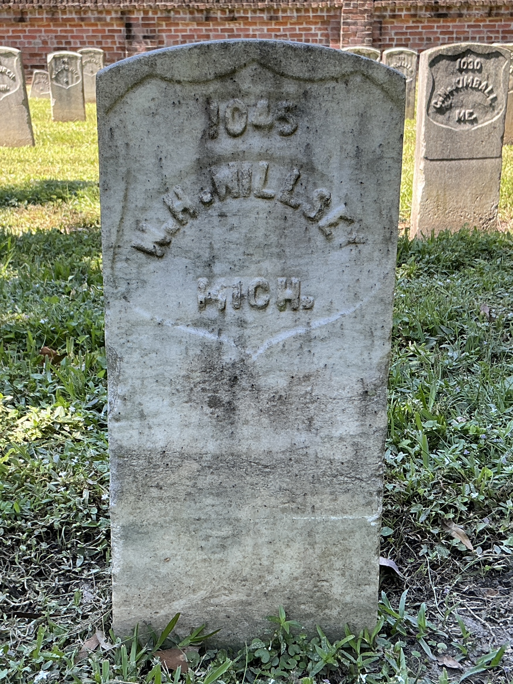 Front of historic upright marble headstone with recessed shield with recessed lettering face.