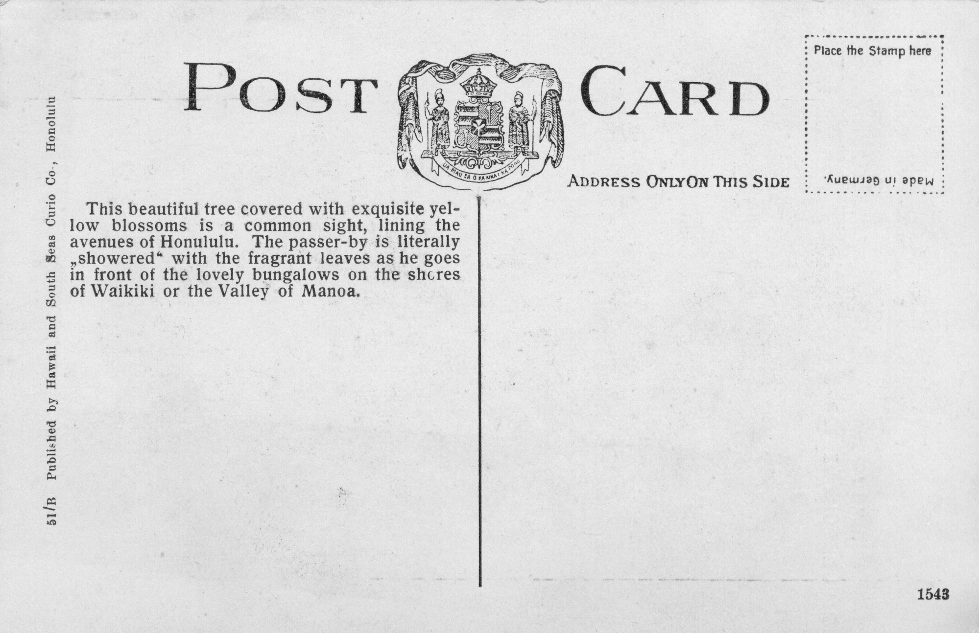The backside of a hand-colored postcard of a golden-shower tree. The words “Post Card” are centered the card. In between the words is the Hawaiian Coat-of-Arms. On the top right corner of the image there is a stamp box outlined by a dotted line. Inside the stamp box are the instructions, “Place the Stamp here.” Also, inside the stamp box, “Made in Germany” is printed upside down along the bottom of the stamp box. The postcard is divided into two halves. On the left side of the image there is a description, “This beautiful tree covered with exquisite yellow blossoms is a common sight, lining the avenues of Honolulu. The passer-by is literally ‘showered’ with the fragrant leaves as he goes in front of the lovely bungalows on the shores of Waikiki or the Valley of Manoa.” Also printed along the left edge of the image is “51/B Published by Hawaii and South Seas Curio Co., Honolulu.” Below “Card” is the subtitle “Address Only on This Side.” There is no address written. On the bottom right corner of the image, “154