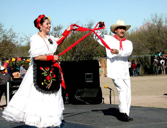 Folklórico dancers at La Fiesta de Tumacácori, man and woman hold red ribbon