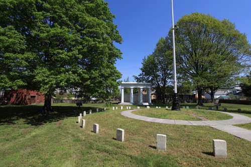 A cemetery with green grass and several headstones of civil war soldiers arranged in a circle. 