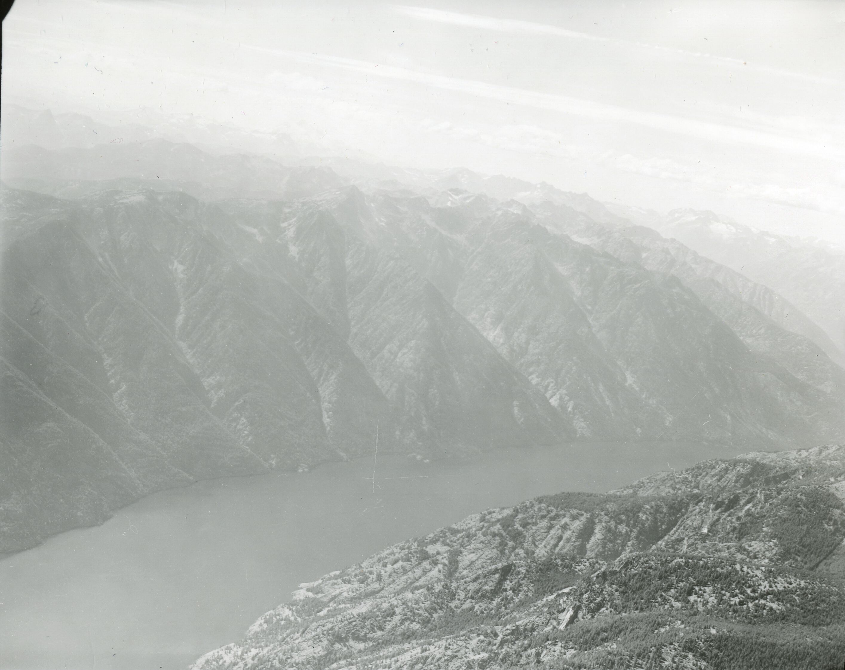 Mountain ridges leading down to a long, still lake.