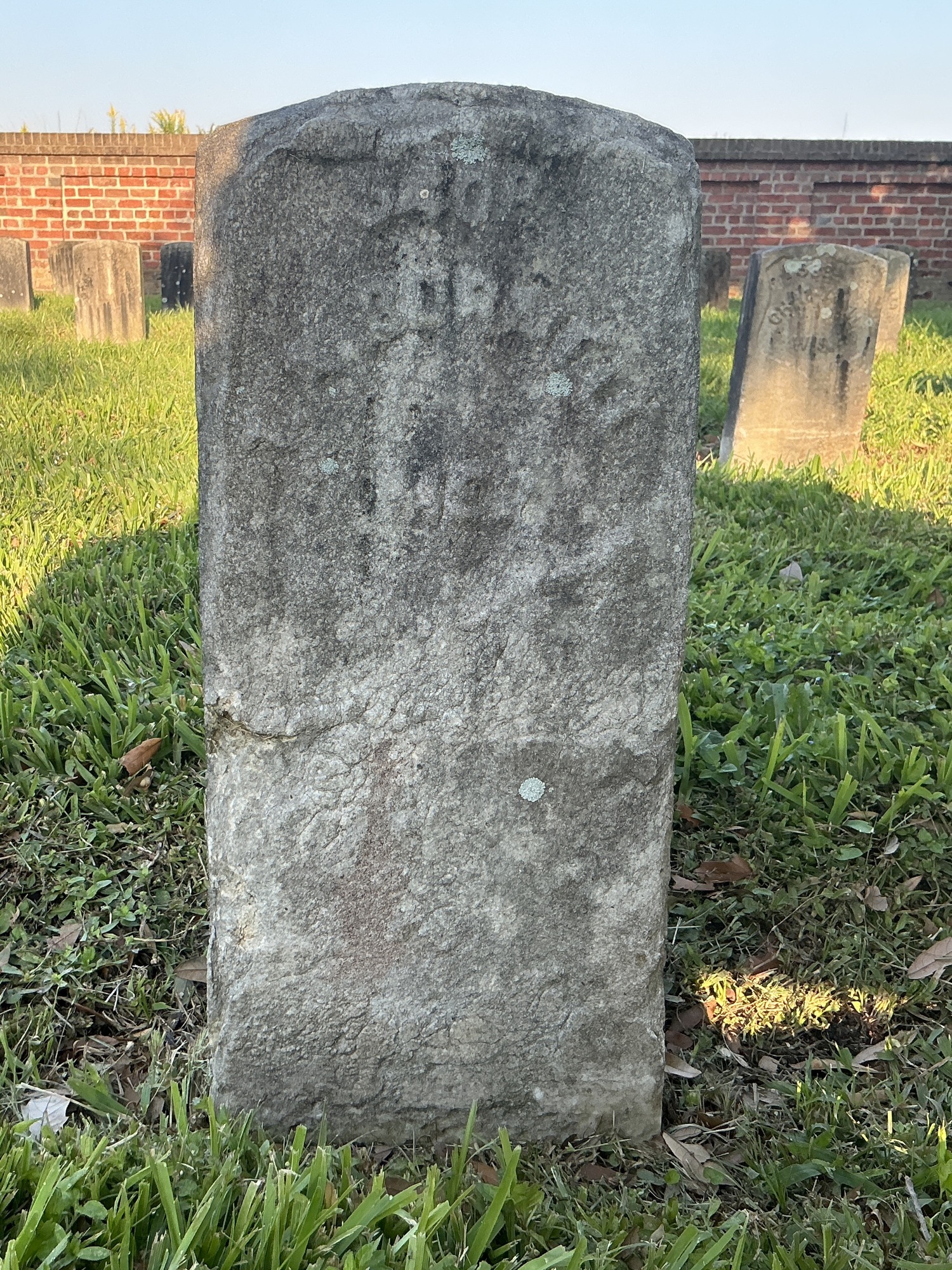 Front of historic upright marble headstone with recessed shield face.