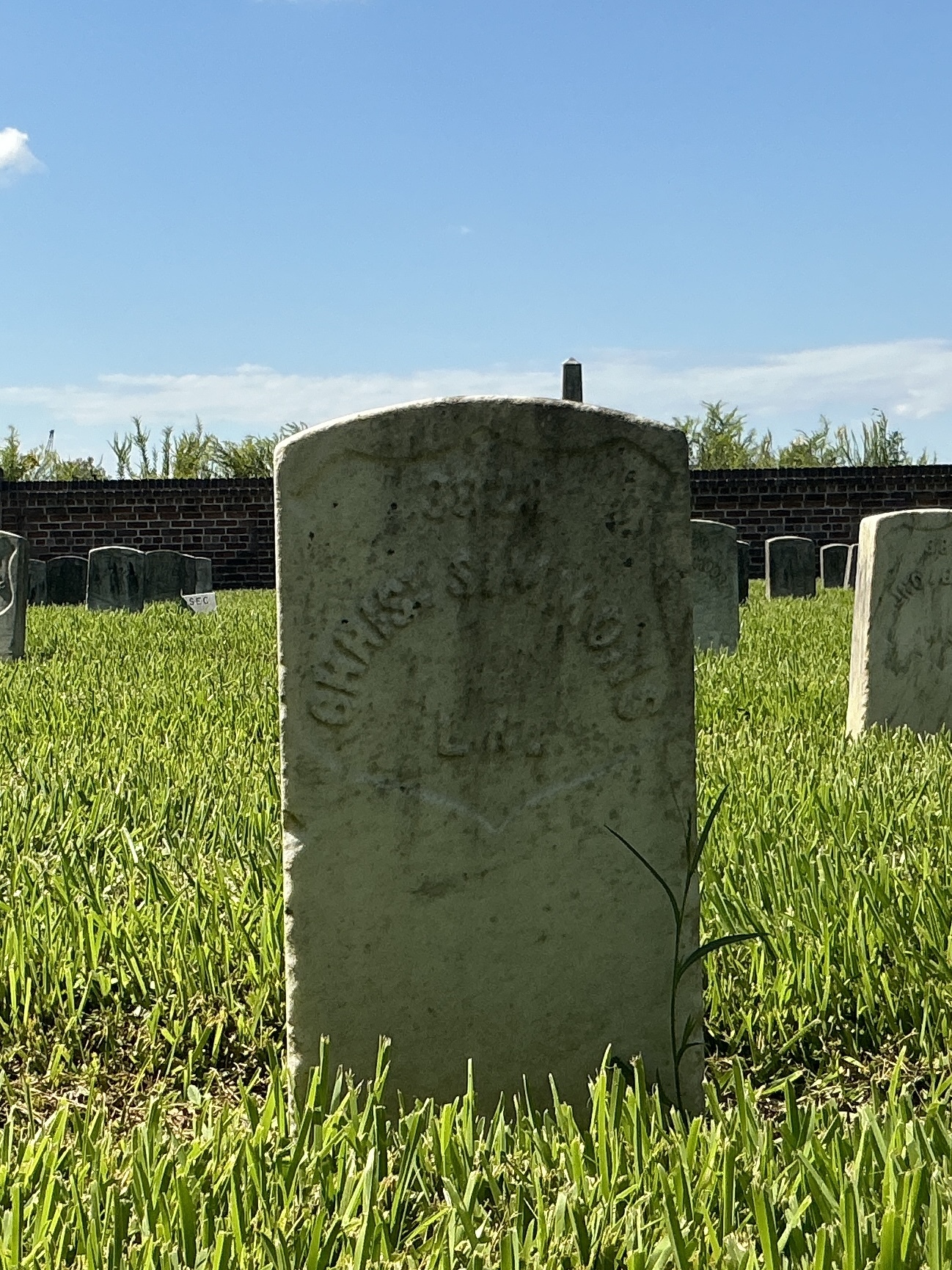 Front of historic upright marble headstone with recessed shield face.