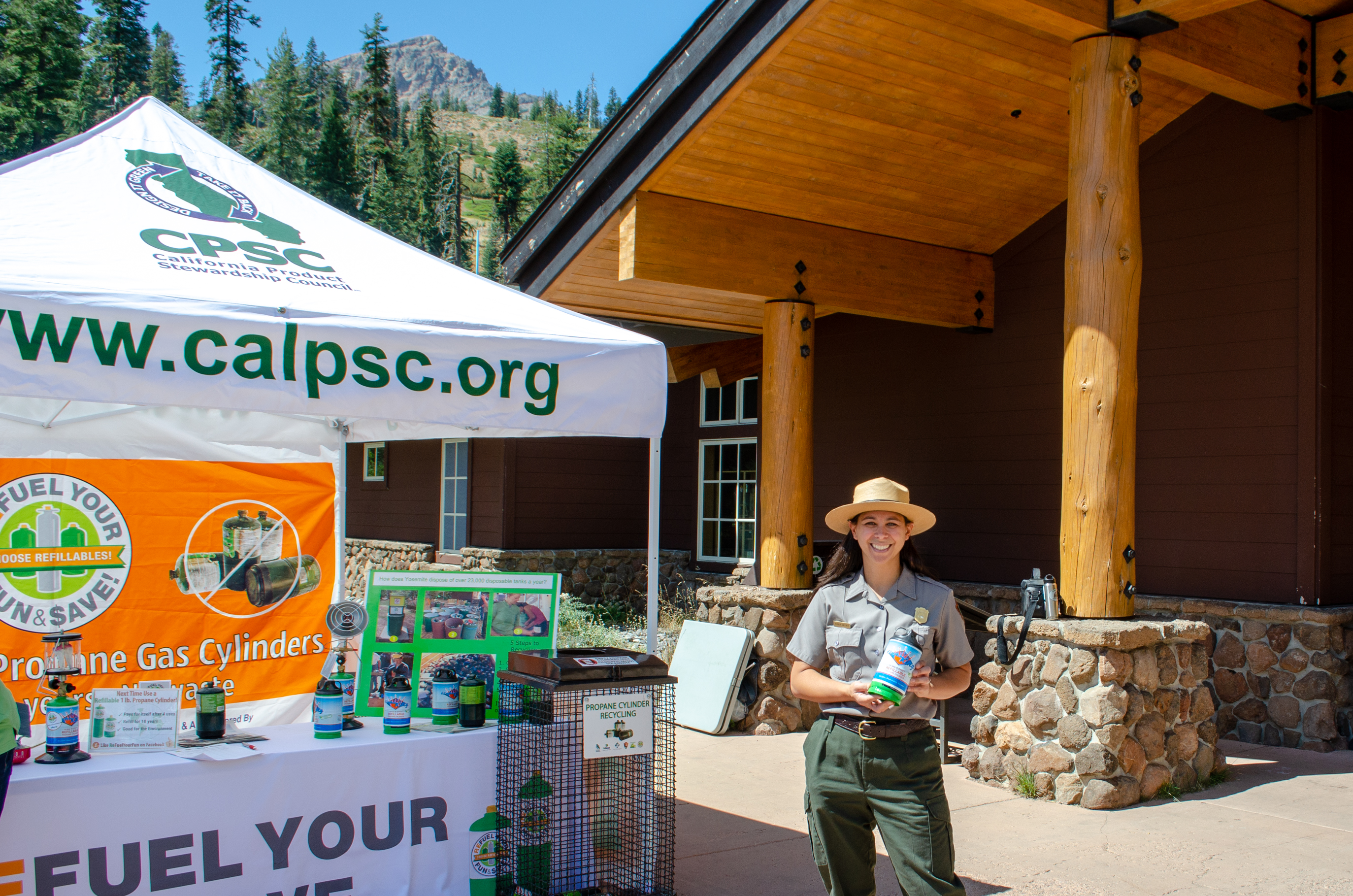 Ranger Amanda holds a refillable propane canister in front of a California Stewardship Council booth for canister exchange outside the Kohm Yah-mah-nee Visitor Center on 8/31.
