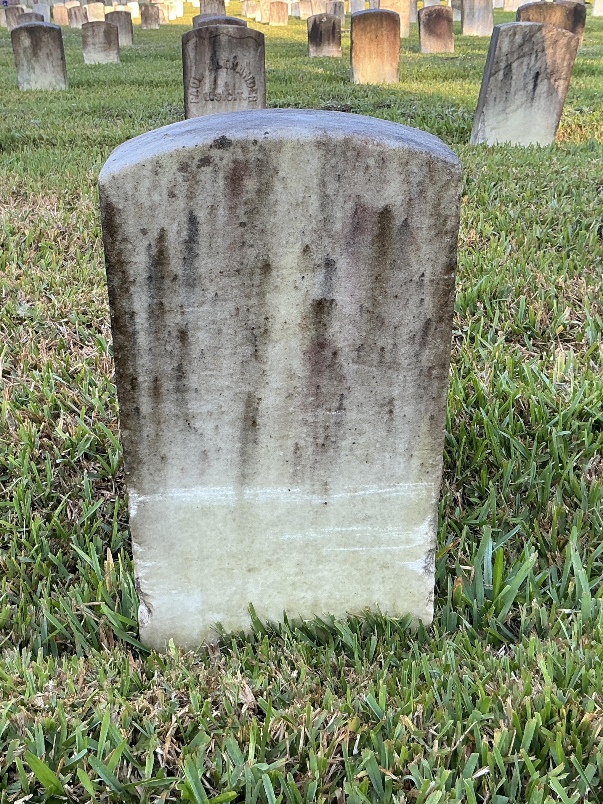 Back of historic upright marble headstone with recessed shield face.