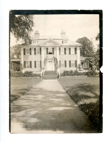 Black and white photograph of long path leading to Georgian mansion.