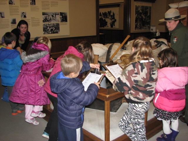 Young students look at a museum display with a ranger explaining the exhibit