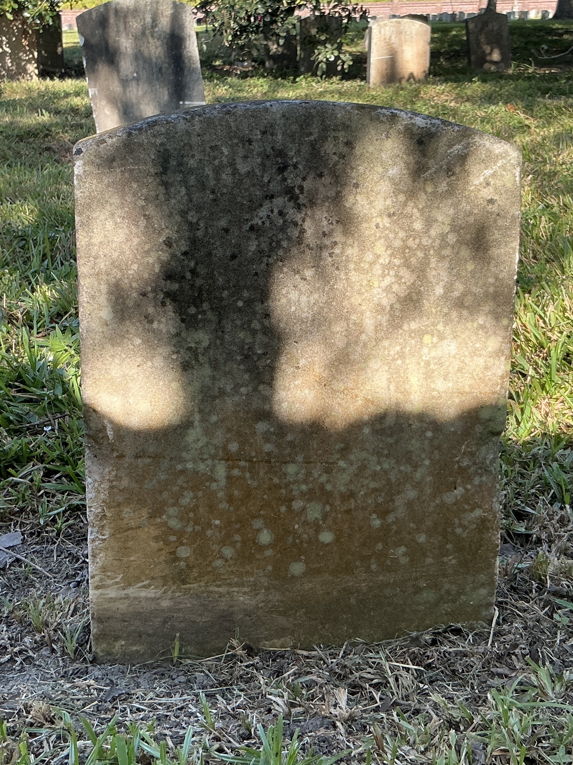 Back of historic upright marble headstone with recessed shield with recessed lettering face.
