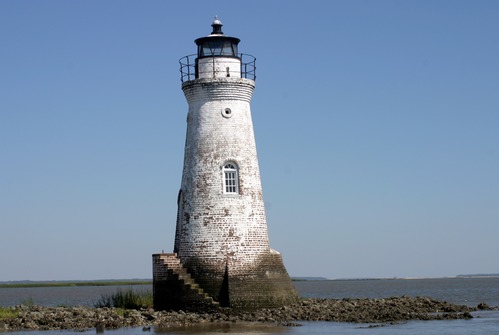A white lighthouse on stoney land. 
