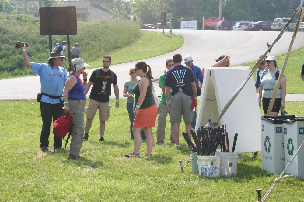 Volunteers pick up equipment to trim vines from trees along the trails.