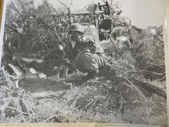 Soldier eating C rations in the field next to a recoiless rifle