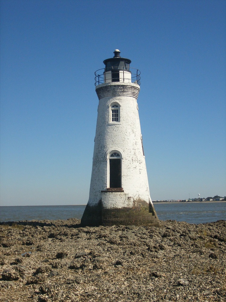 White lighthouse on a rough shore. 