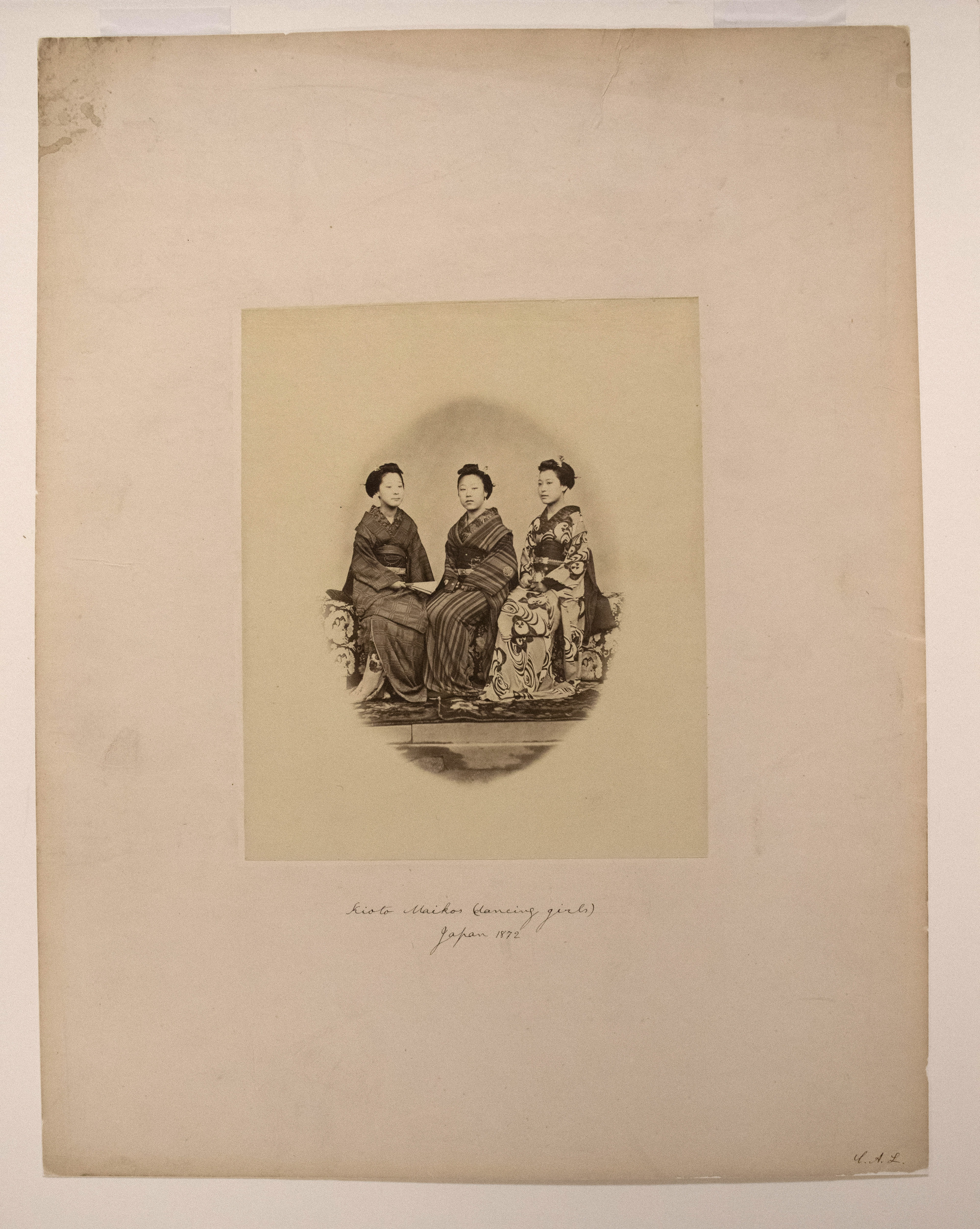 Sepia photograph with an inscription representing a group of several dozen of Japanese girls and a white woman posing at the steps of a large building.