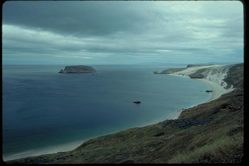 View of Cuyler Harbor and Prince Island from San Miguel Island with sand dunes on far end of beach.