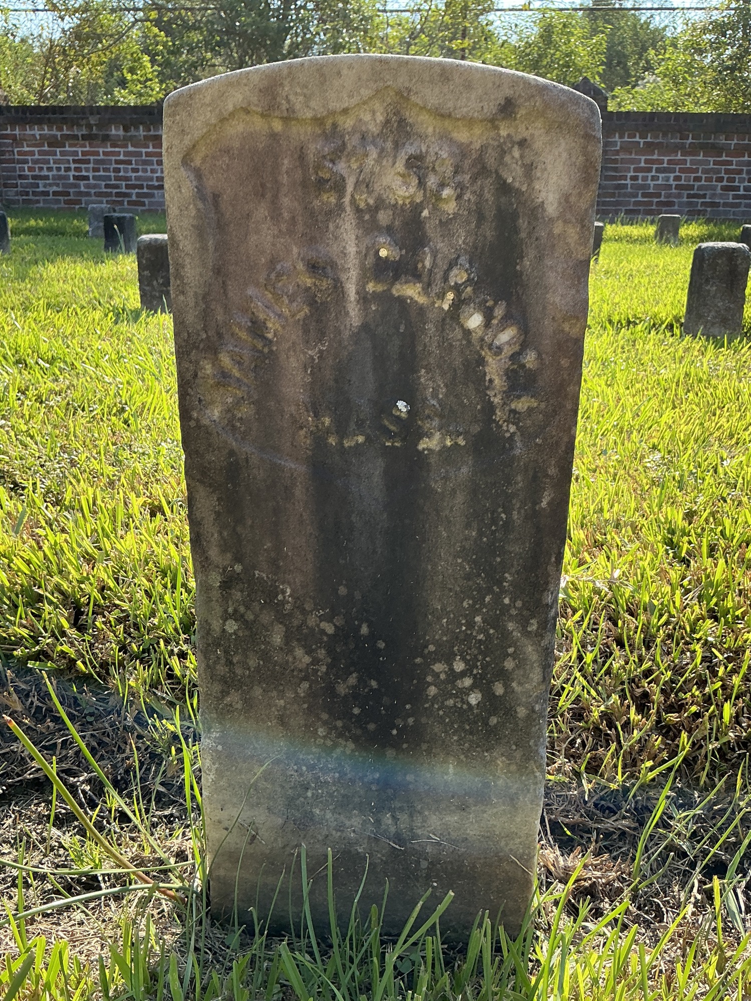 Front of historic upright marble headstone with recessed shield face.