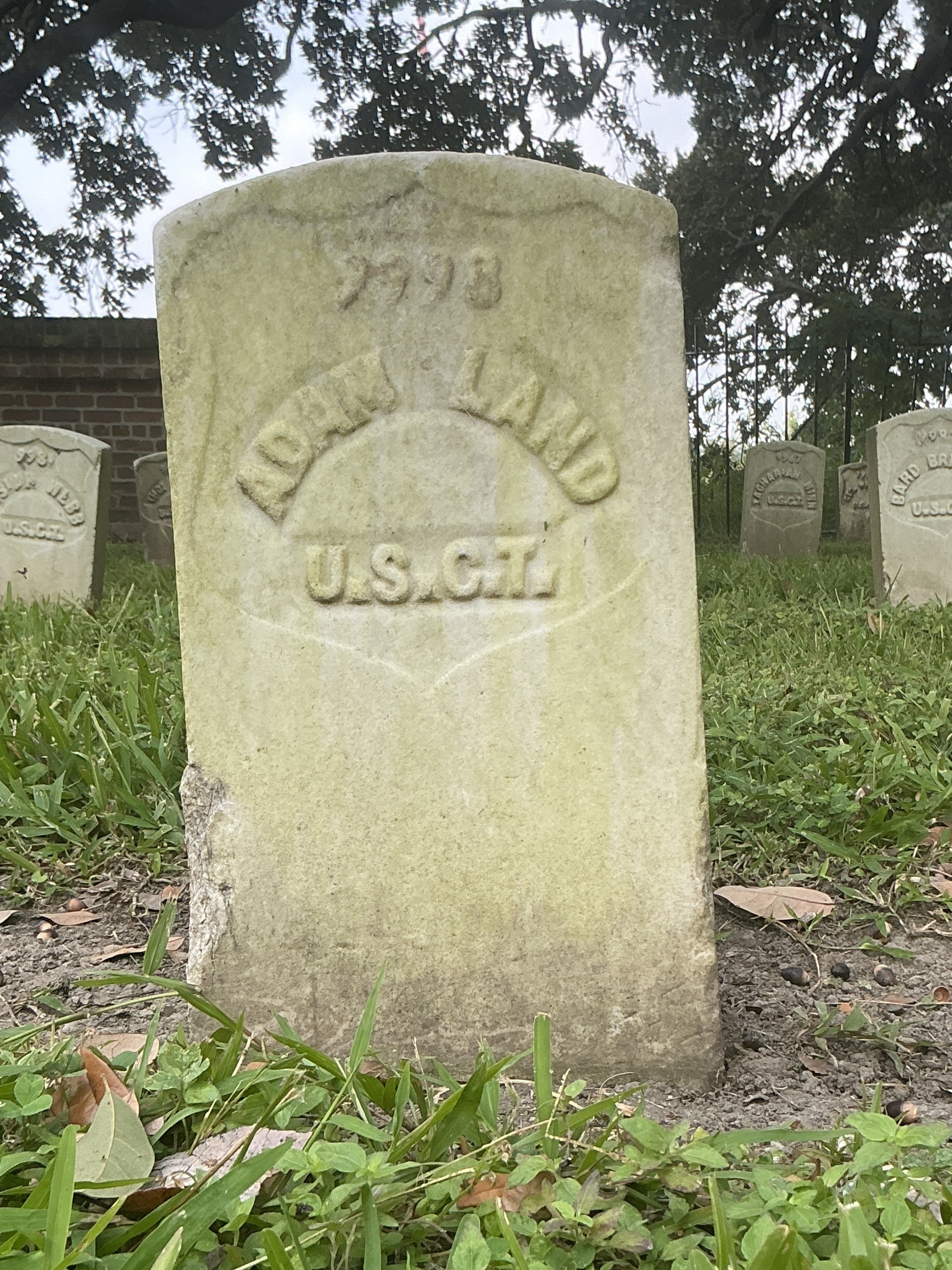 Front of historic upright marble headstone with recessed shield with recessed lettering face.