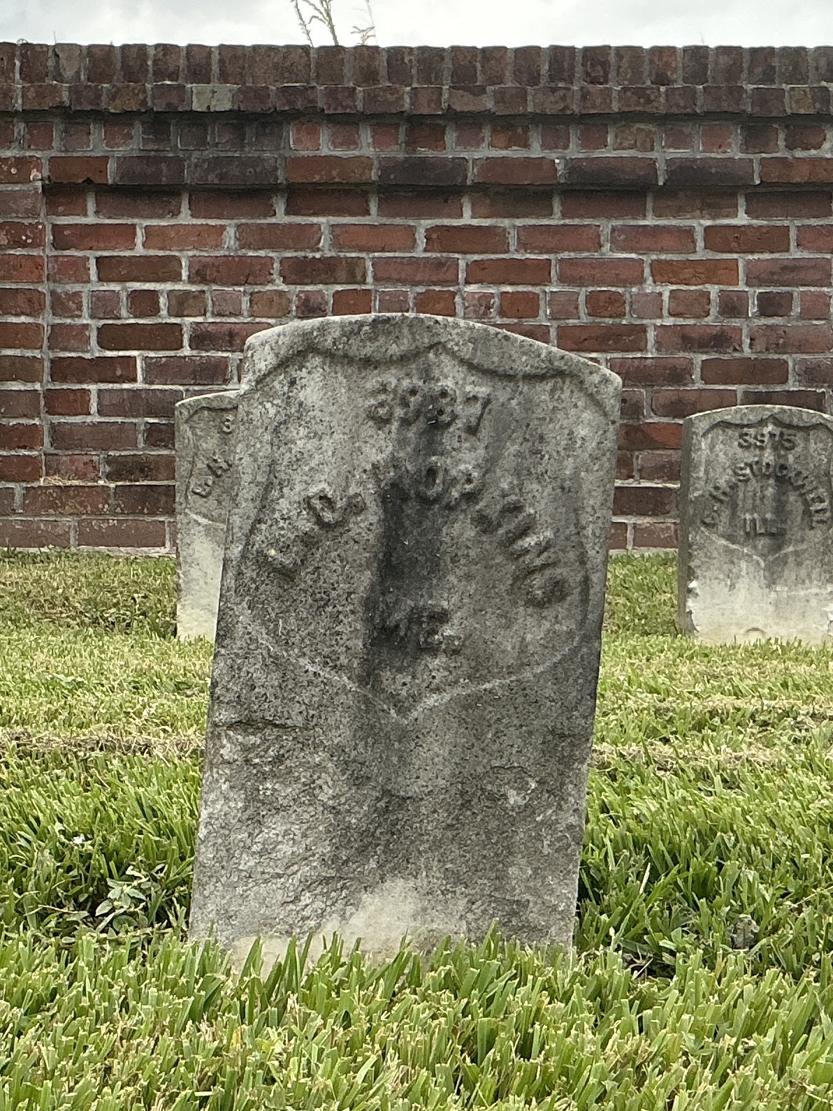Front of historic upright marble headstone with recessed shield face.