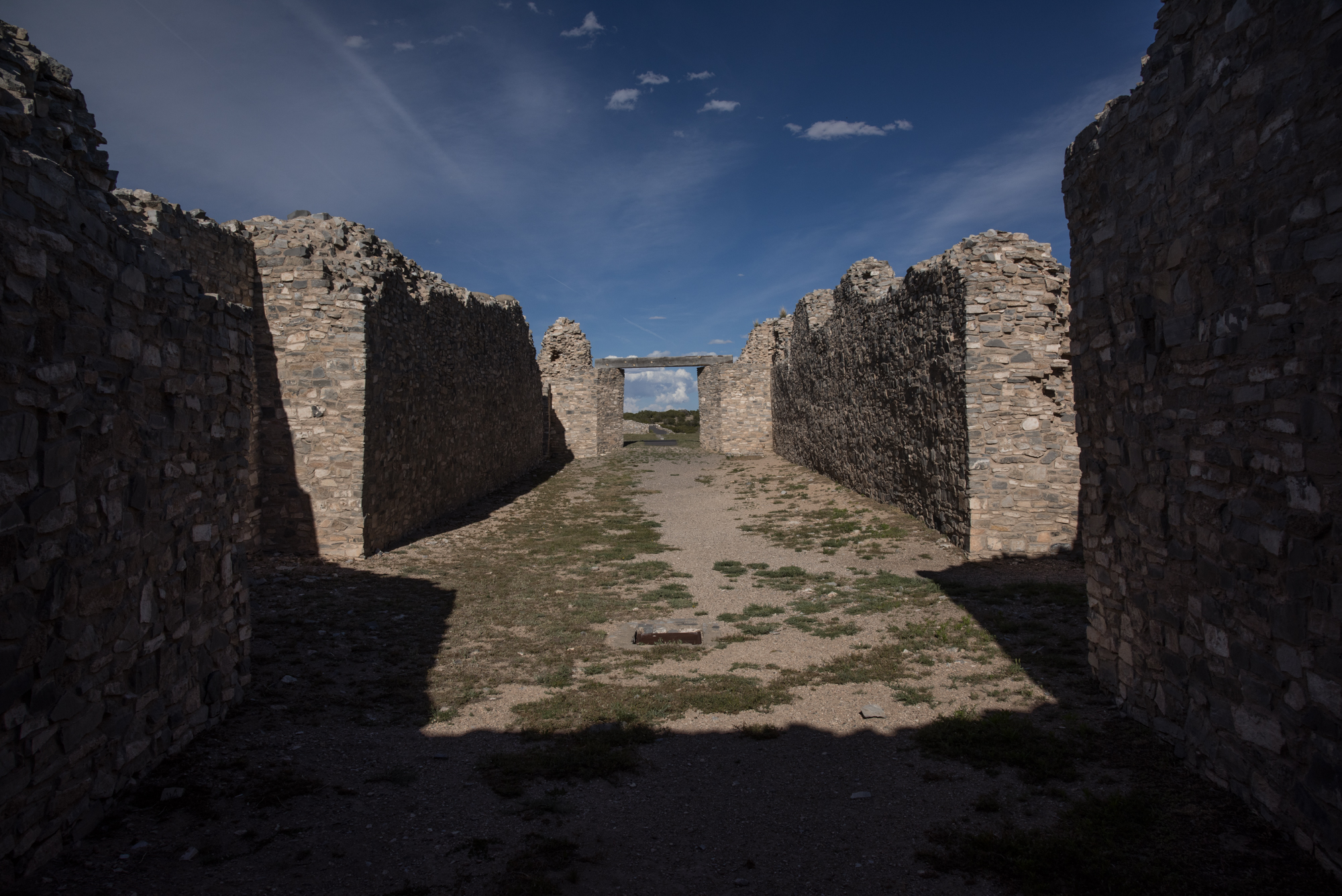 Inside the ruins at Gran Quivira. The mission walls form both sides of the picture. The old mission doors, which are no longer existing, is in the center of the picture. A blue sky is over head. 