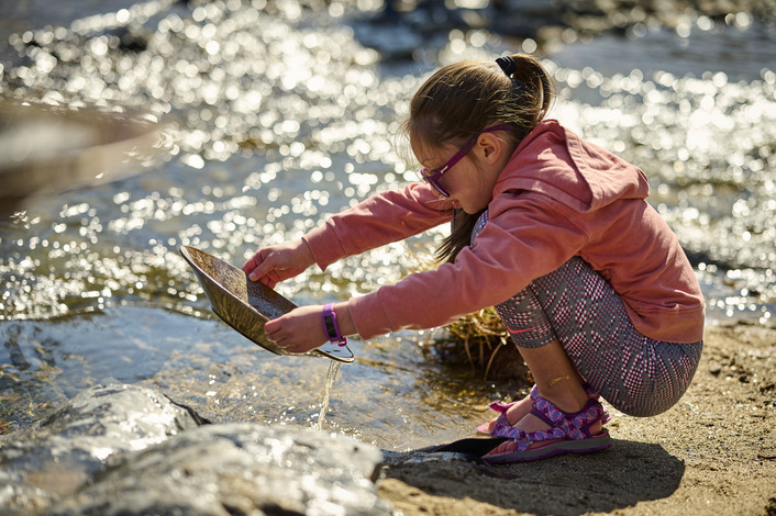 A student gold panning in a creek.