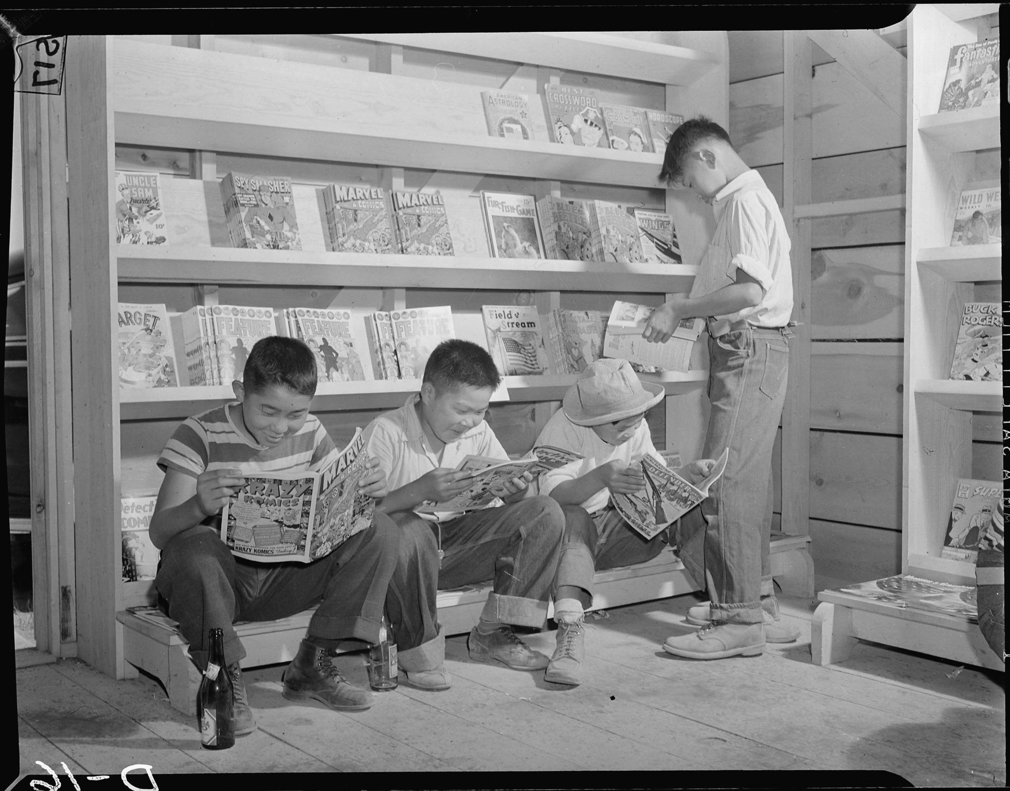 Four little evacuees from Sacramento, California, read comic books in the newstand at this War Relocation Authority center for evacuees of Japanese descent