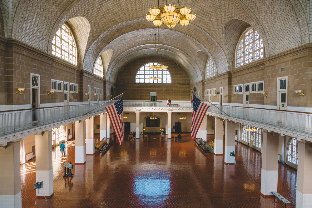 Large room with terra cotta-colored tile floor, a balcony, large arched windows, and creamy white tiled vaulted ceiling.