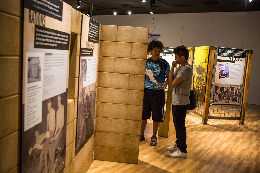 College age visitors stand before a tall exhibit kiosk