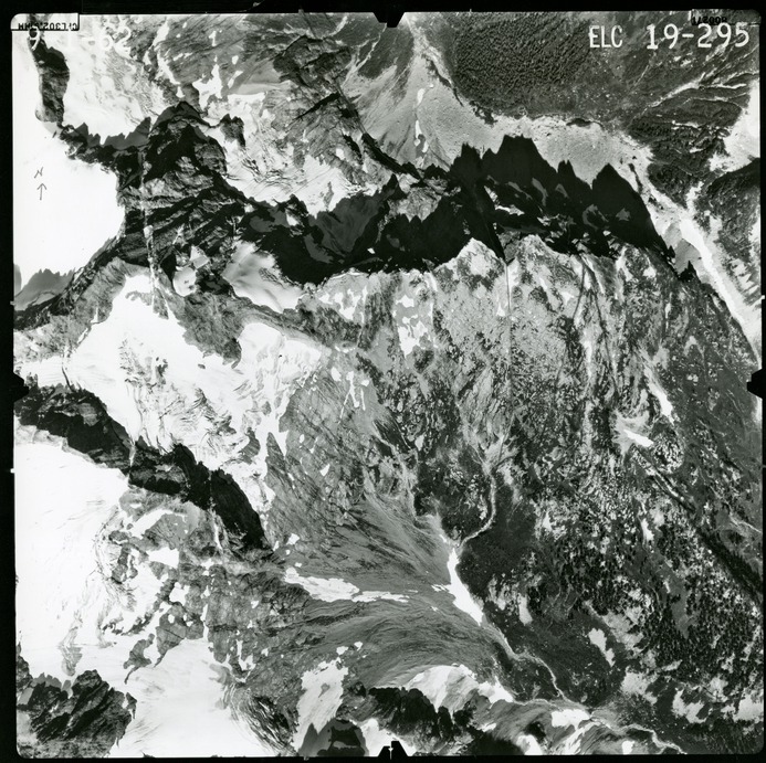 Black and white aerial photograph of glaciated mountain peaks and valleys.