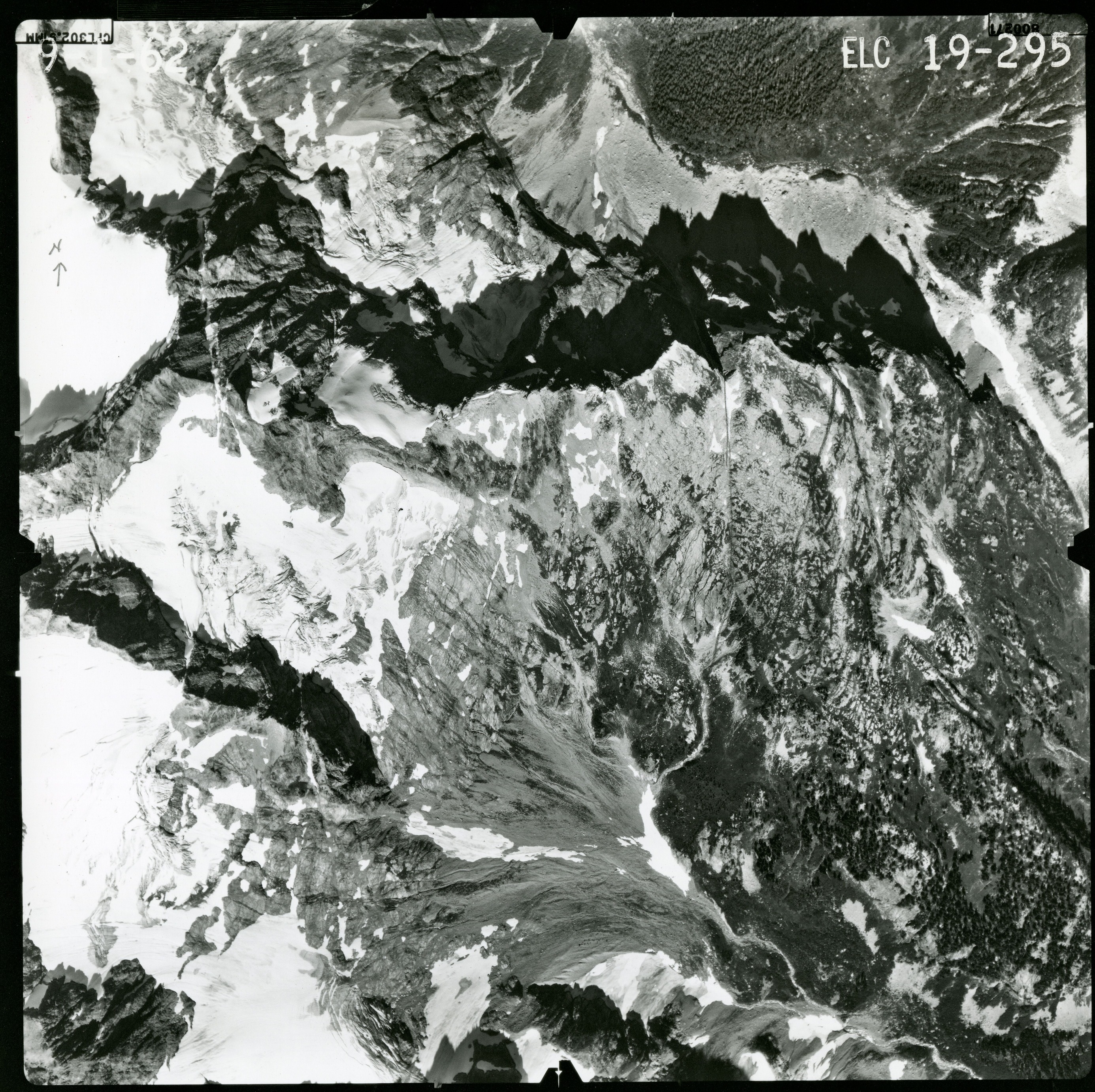 Black and white aerial photograph of glaciated mountain peaks and valleys.