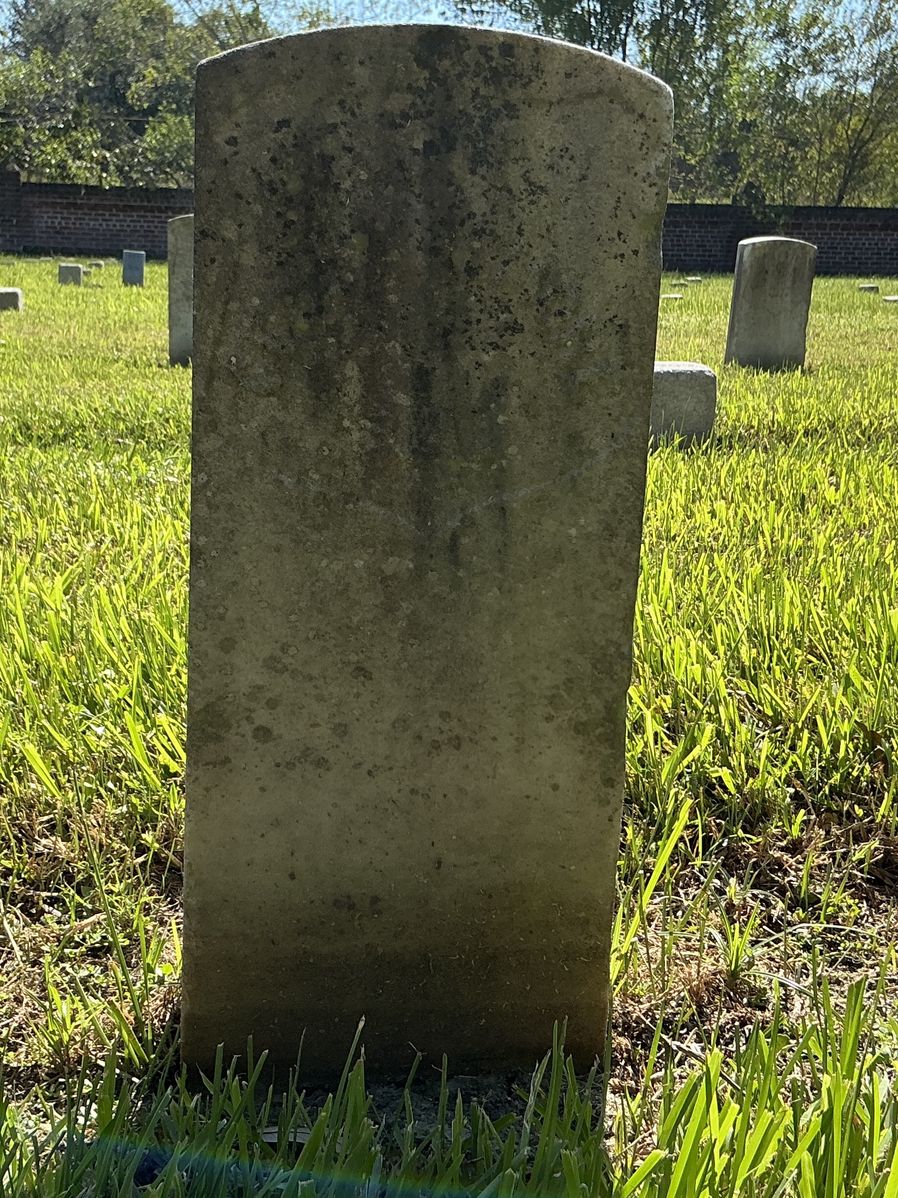 Front of historic upright marble headstone with recessed shield face.